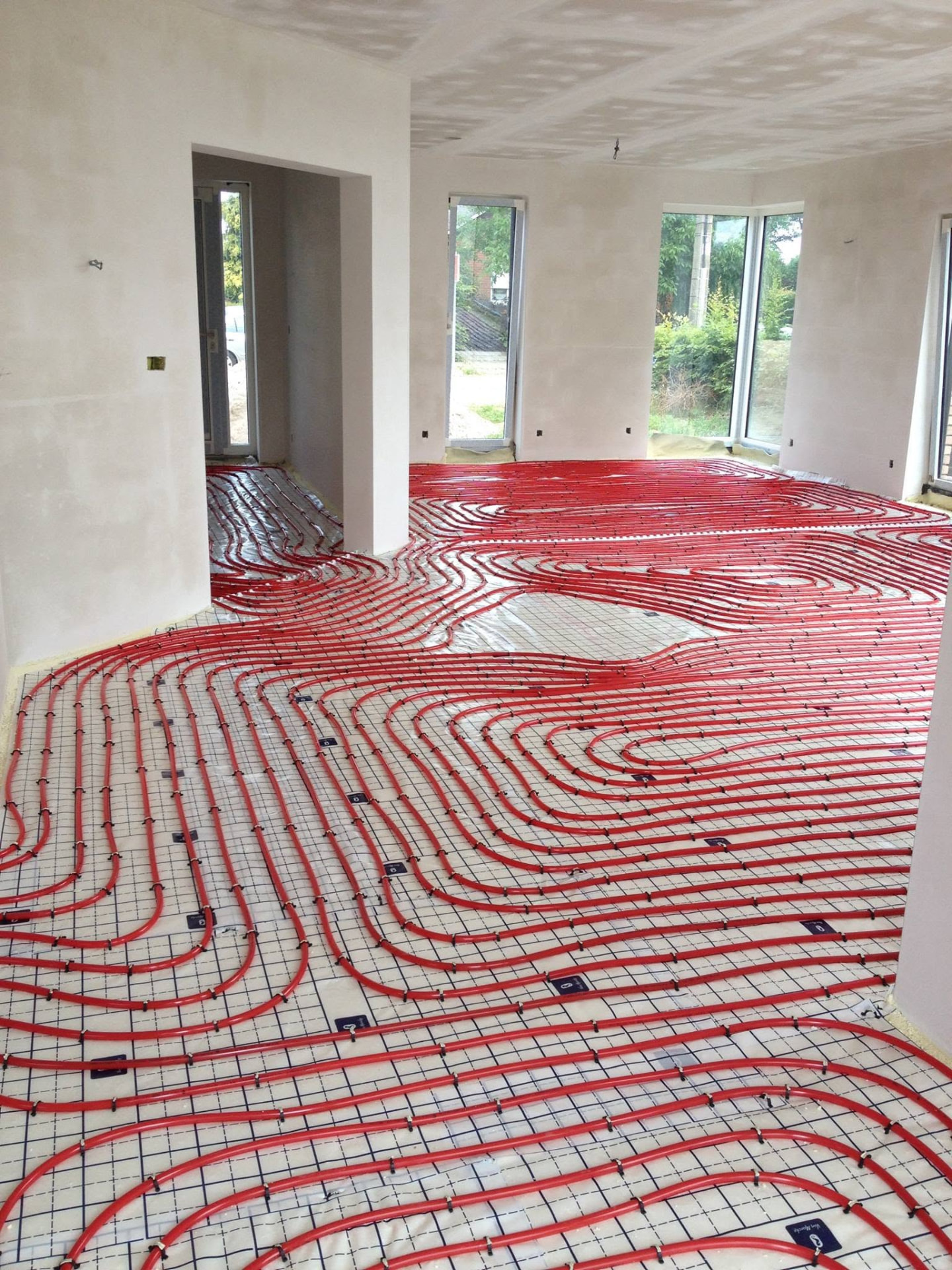 Boucles rouges de chauffage par le sol posées dans un séjour neuf par Energies Concept à Fleurus