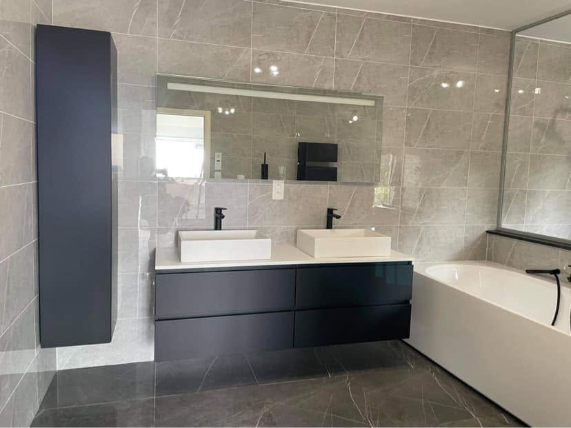 Baignoire îlot et grand miroir dans une salle de bain rénovée par Energies Concept à Nivelles